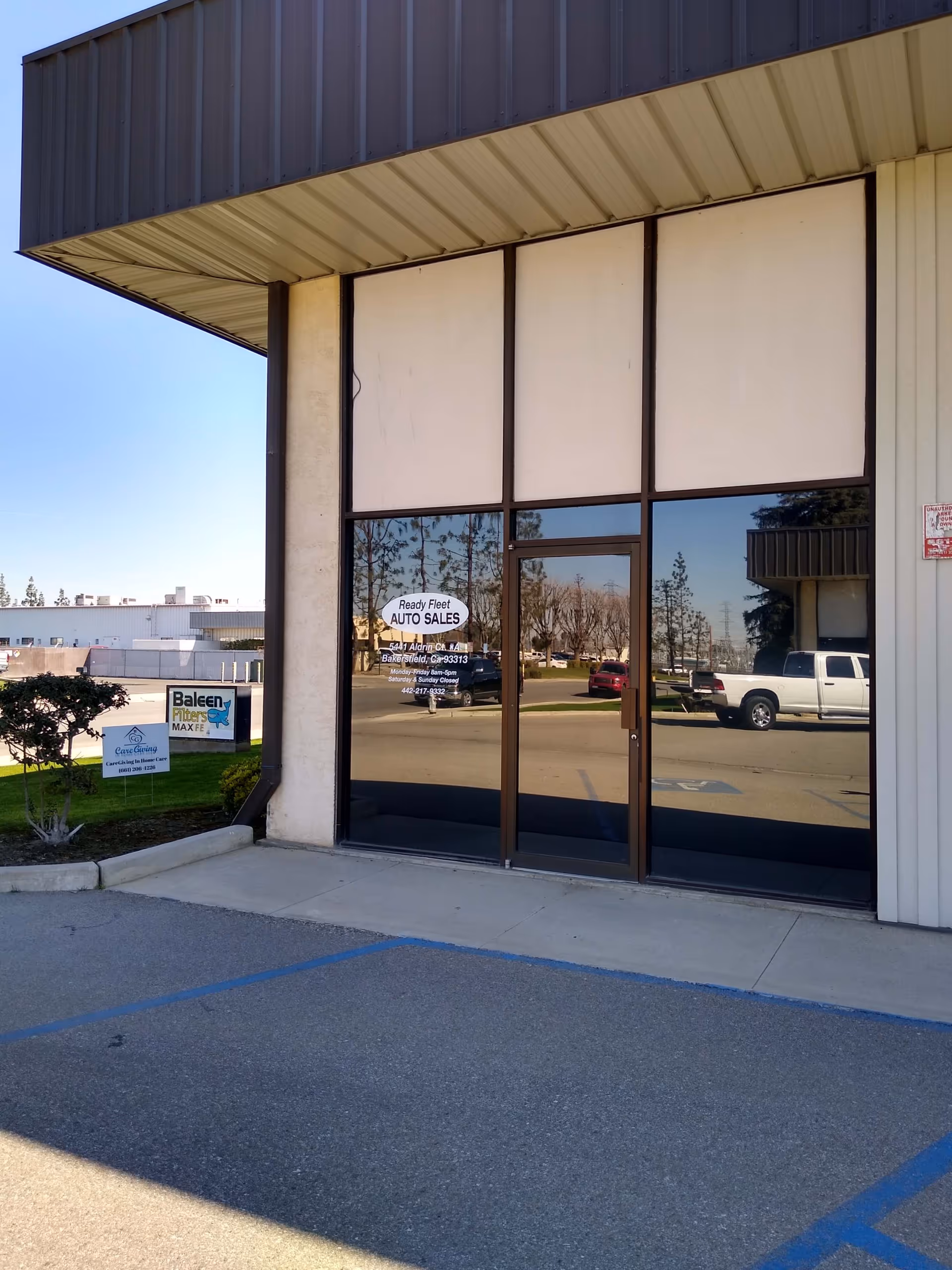 Front of a building with glass doors and large windows under a metal canopy.