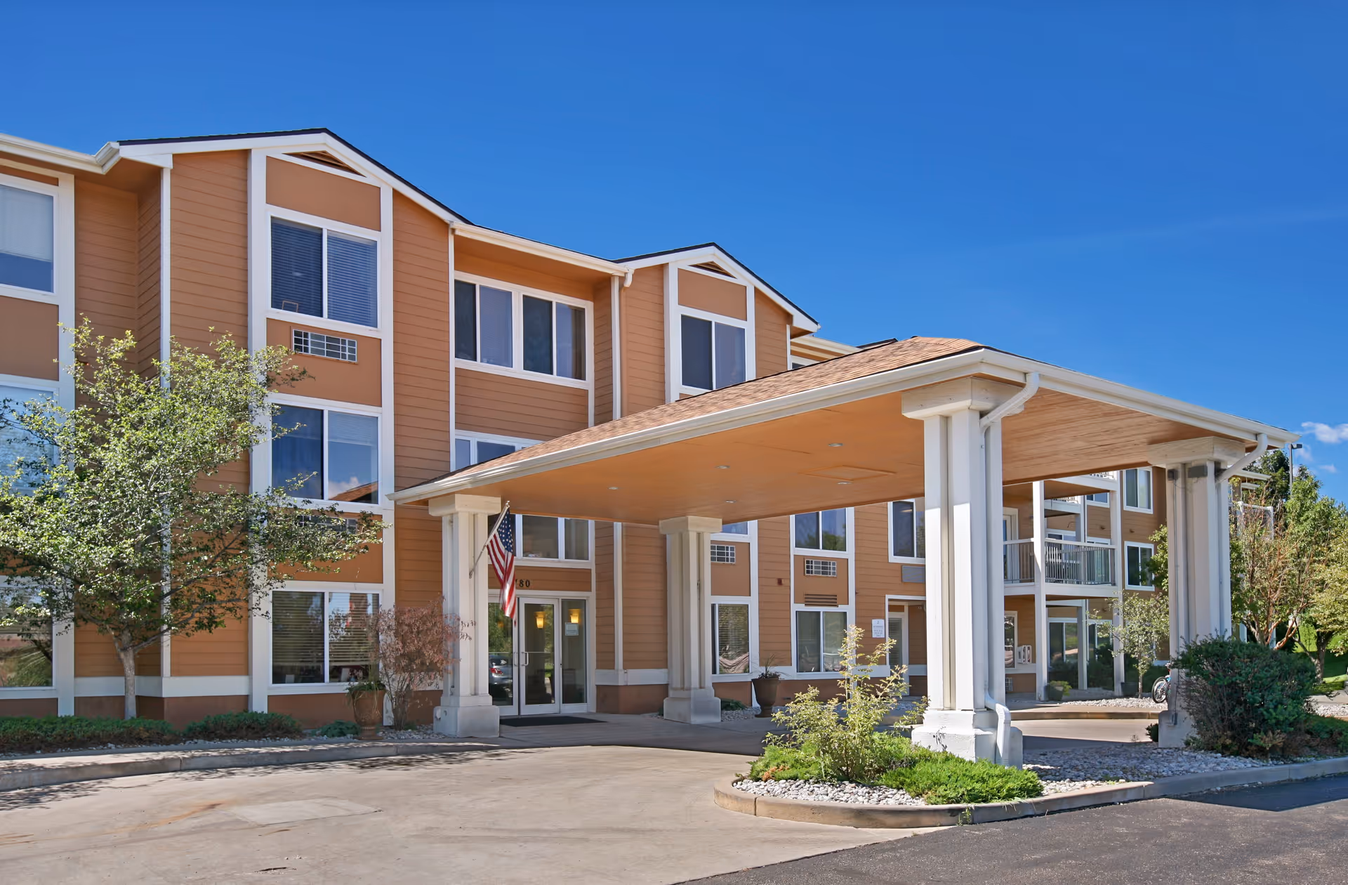 Sunlit exterior of Brookdale Vista Grande with a covered entrance and airy facade.