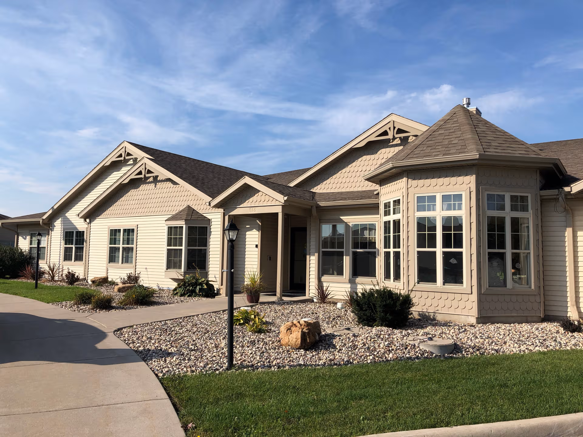 Beige, single-story memory care facility exterior with rock landscaping.