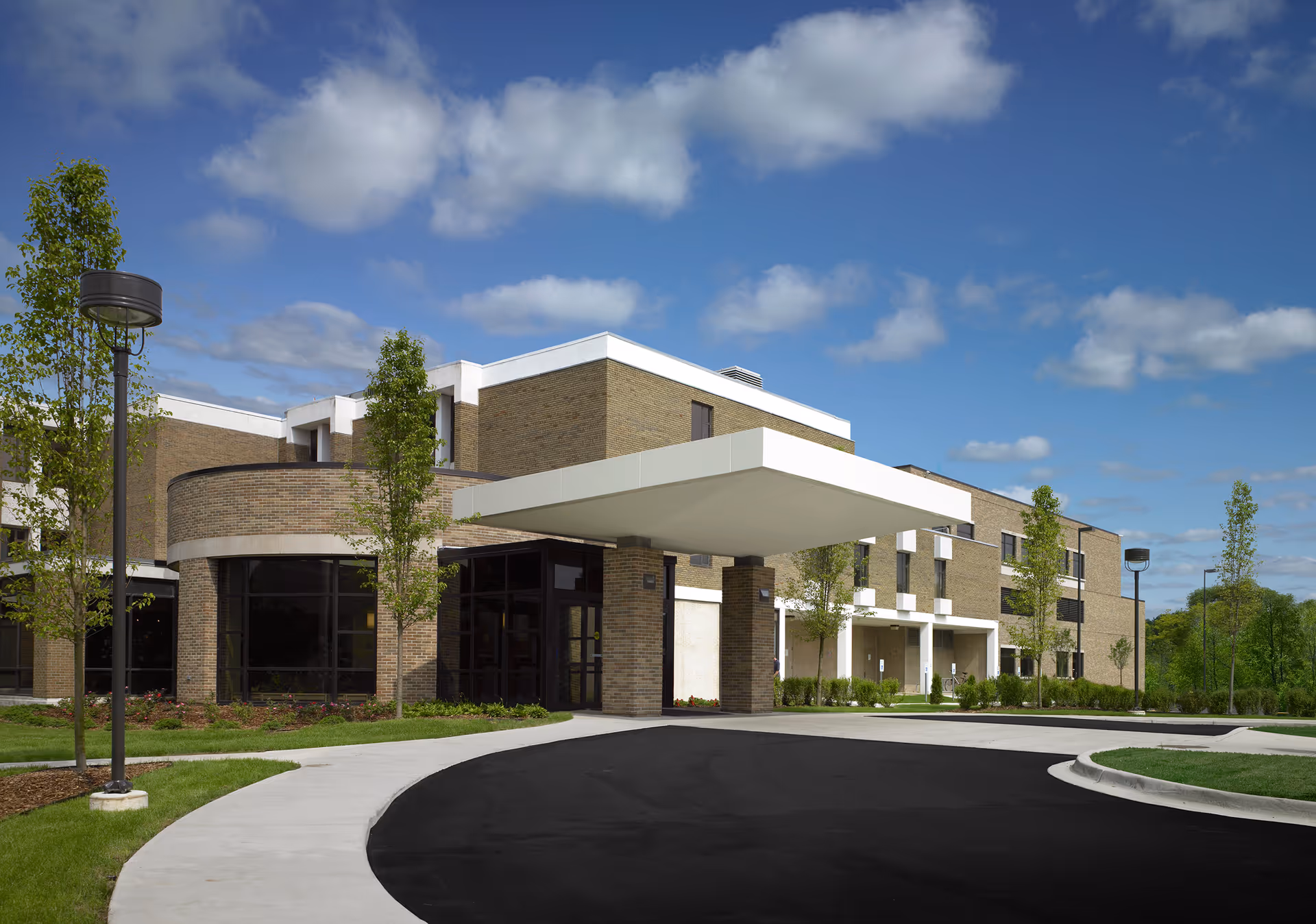 Exterior view of a brick senior living facility front entrance with a curved driveway.