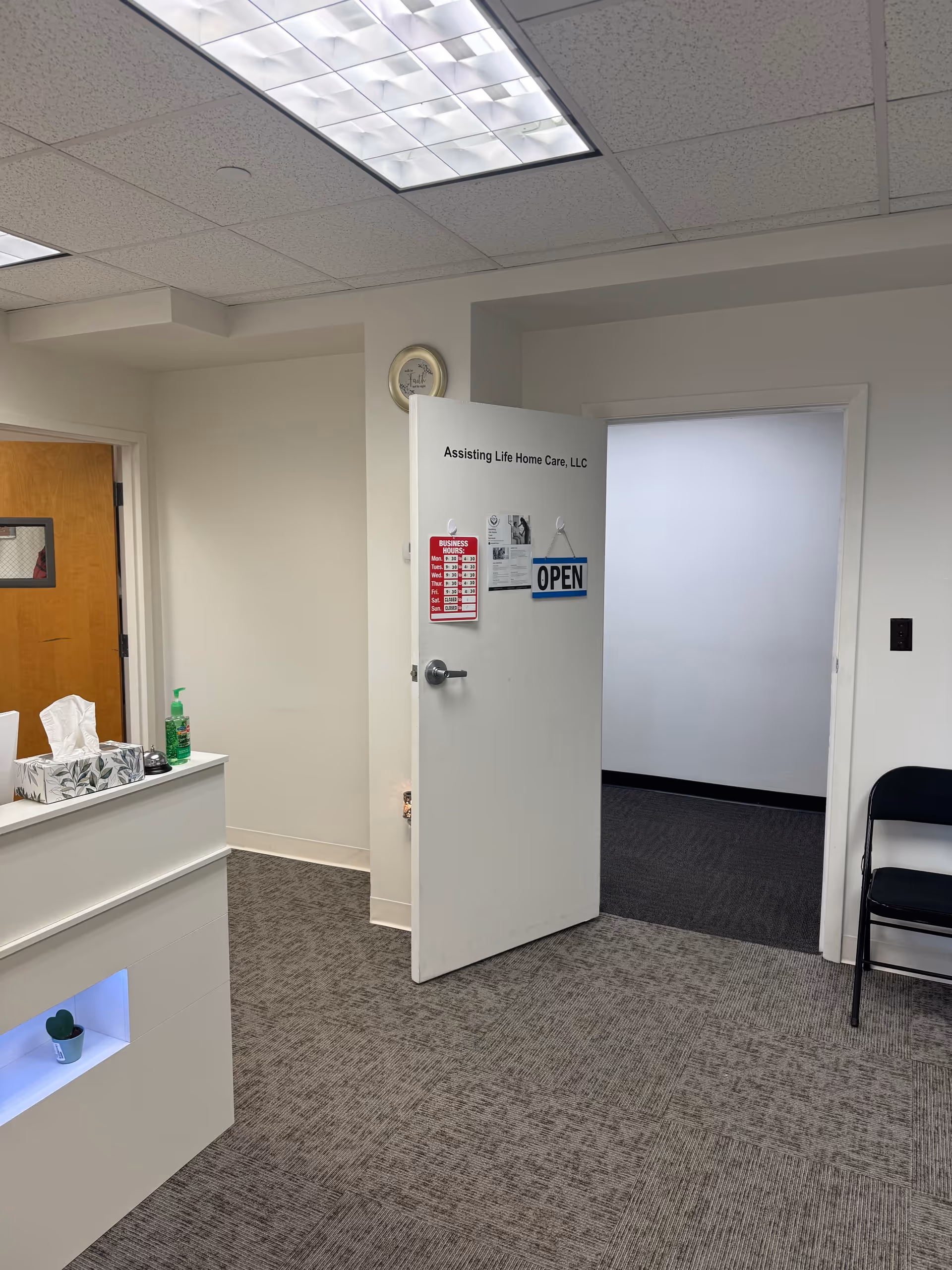 Reception area with open door labeled Assisting Life Home Care, LLC, open sign, and seating.