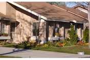 Single-story beige senior living facility with landscaped front yard and planters.