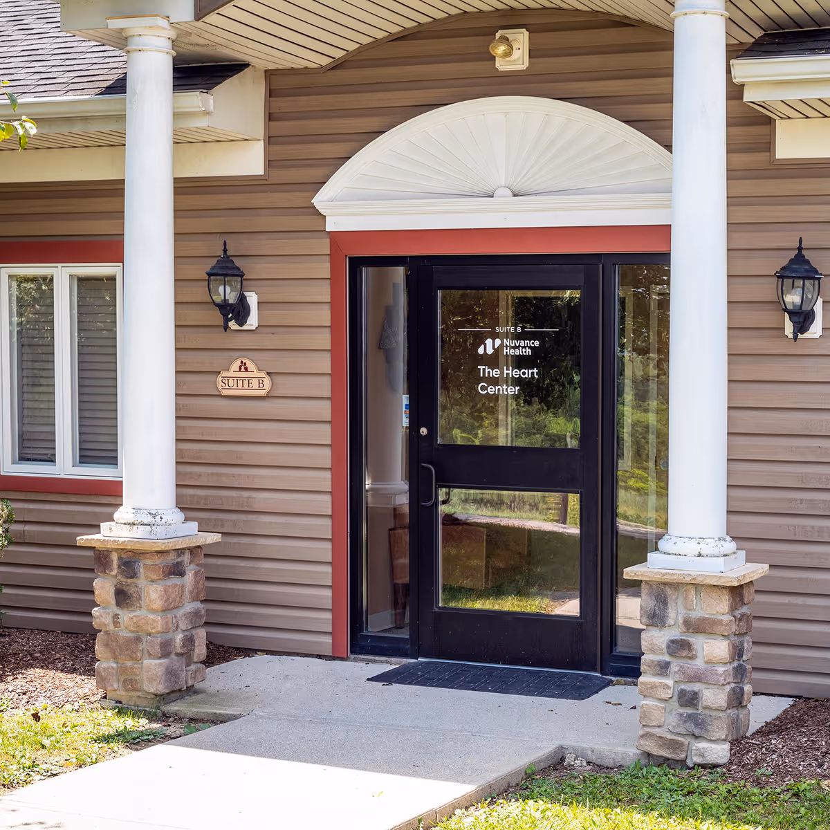 Entrance to The Heart Center with black door, columns, and stone base.