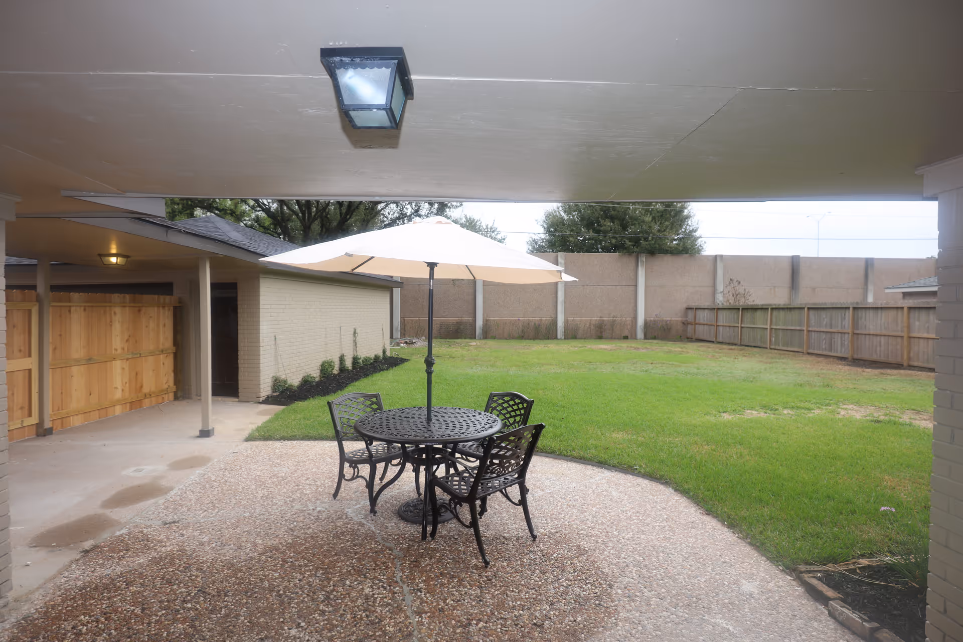 Outdoor patio with a round metal table, four chairs, and a white umbrella.
