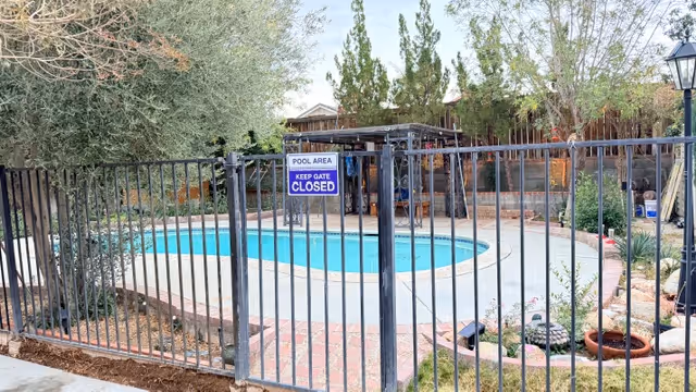 Outdoor pool area at Adelanto Care Manor, fenced with a Pool Area Keep Gate Closed sign.