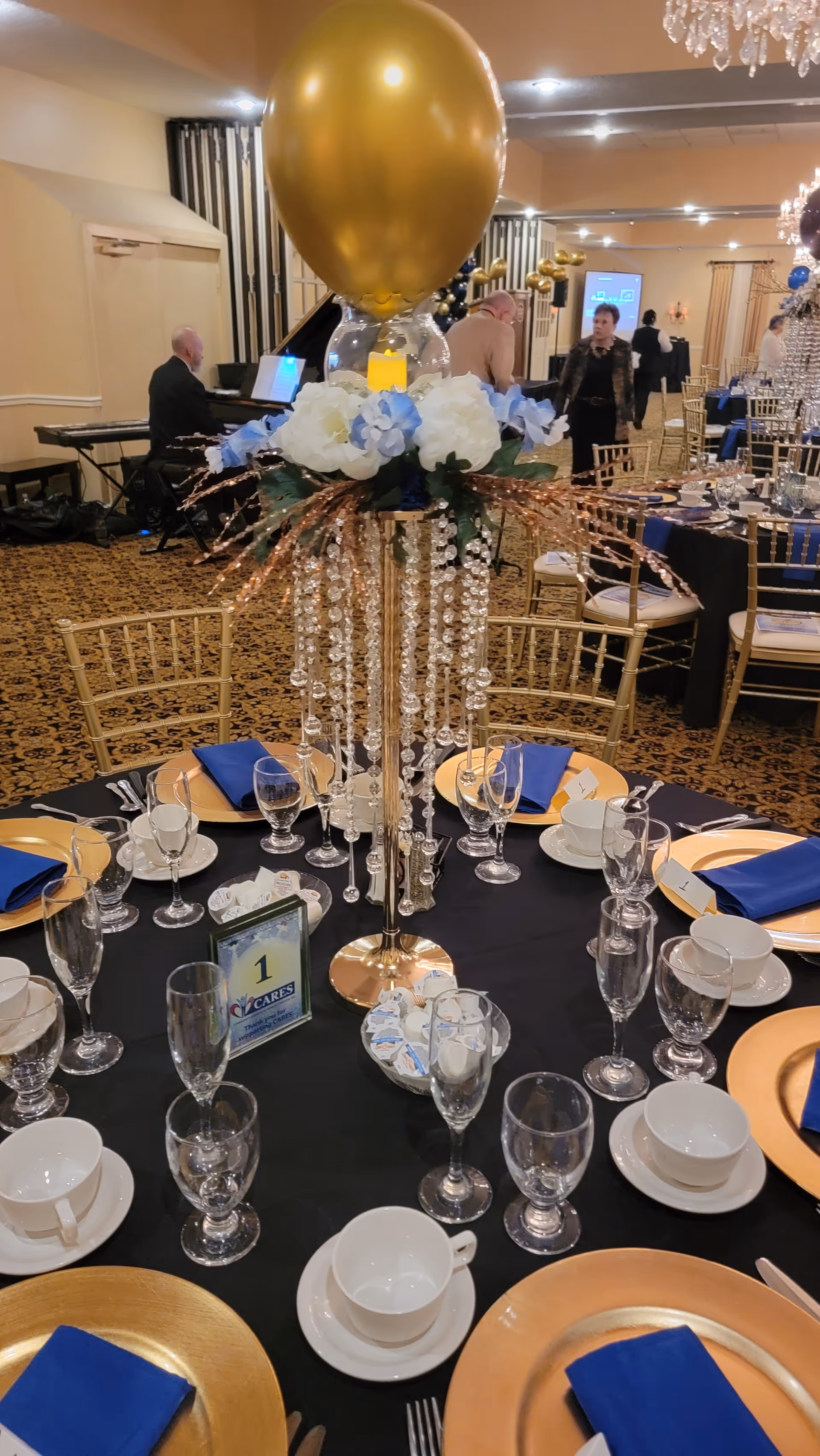 Elegant banquet tables in a dining hall with gold chairs and crystal centerpieces.