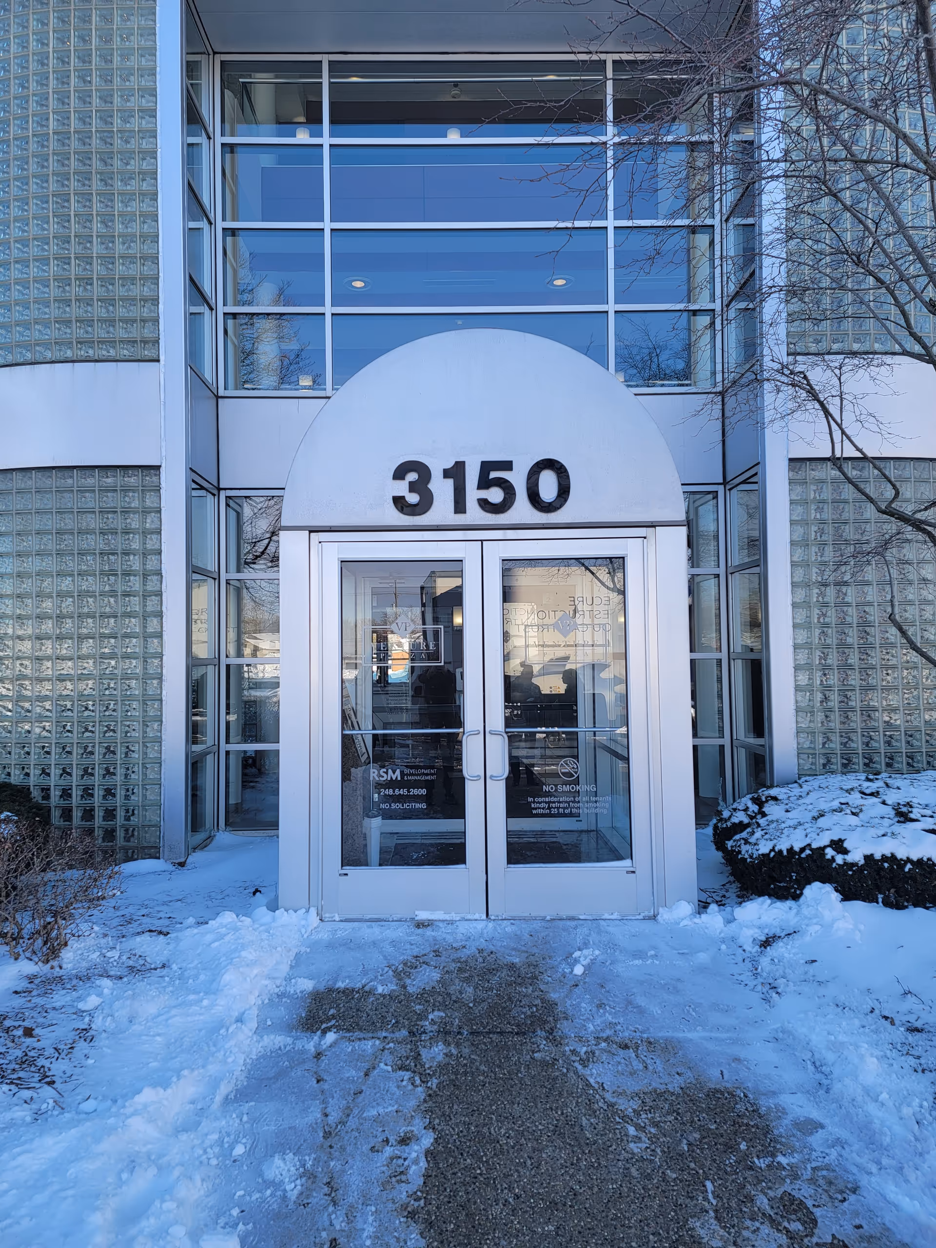 The exterior entrance of Fusion Home Health Care Agency features glass doors and a snow-covered walkway.