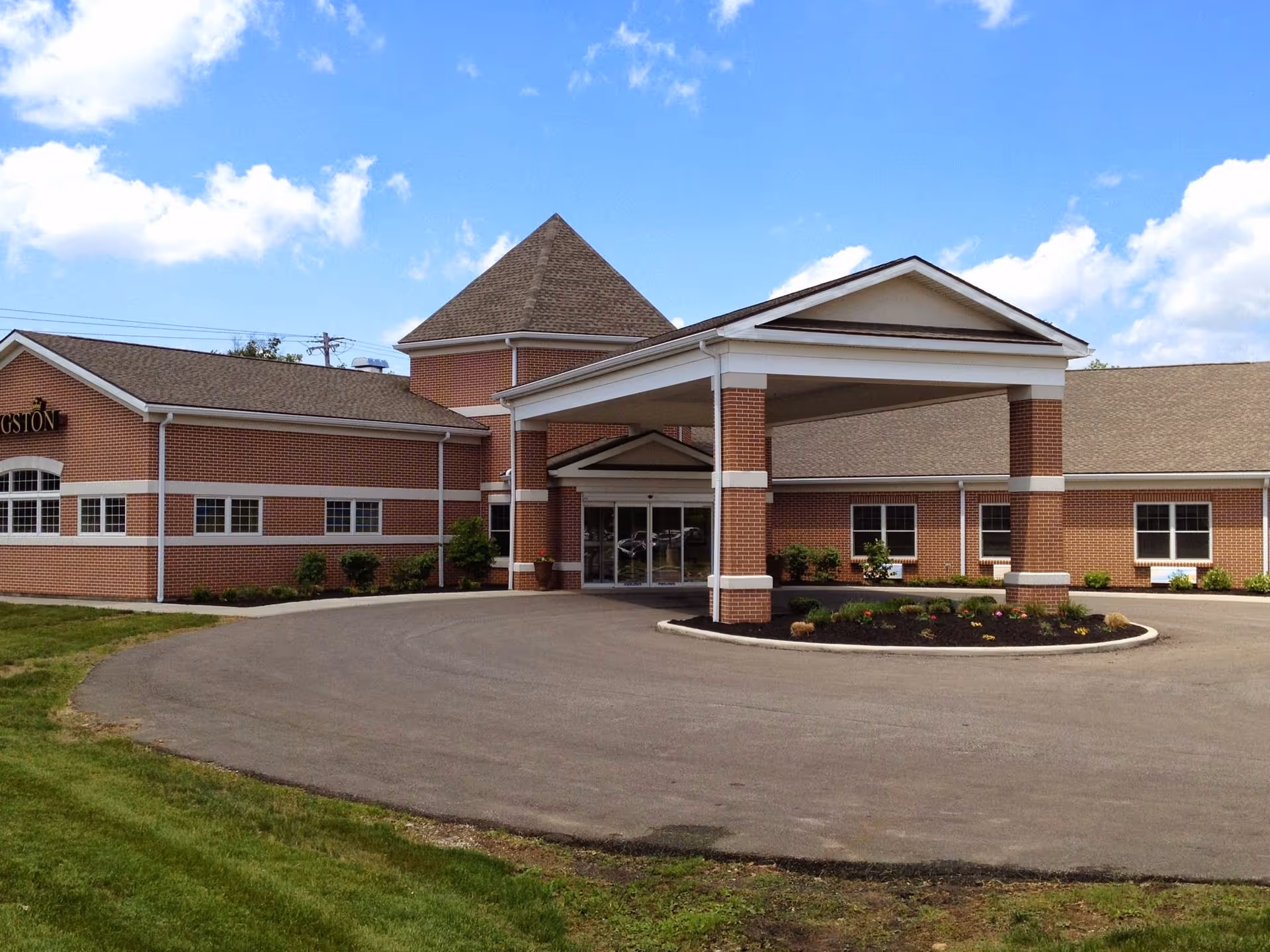Exterior view of Kingston of Ashland, brick senior living facility with a covered front entrance.