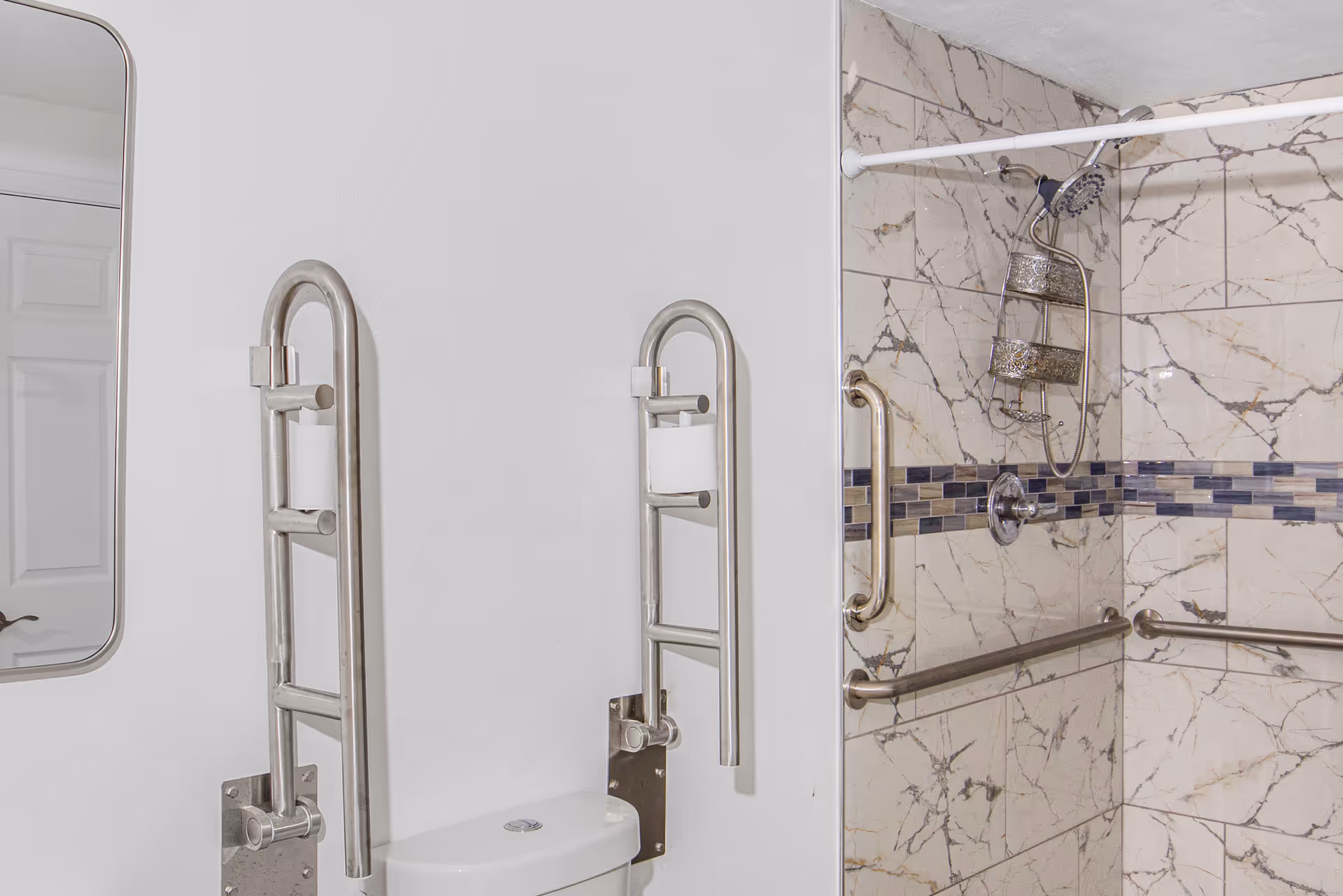Accessible bathroom with vertical grab bars, marble tiled shower, and toilet area.