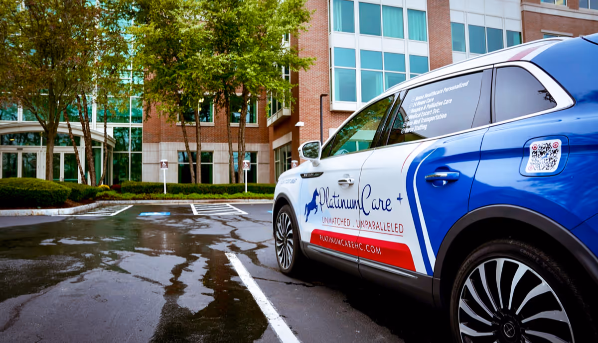Blue and white PlatinumCare vehicle parked outside a brick senior living facility entrance.