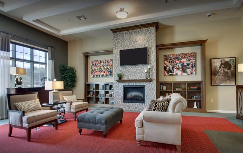 Spacious living room in a Guest House Ocala facility with armchairs, fireplace, TV, and bookshelves.
