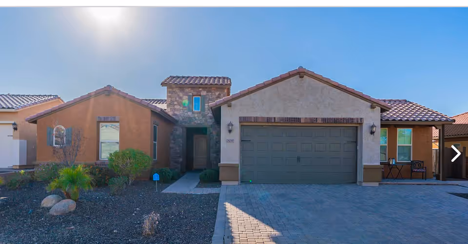 Front view of a single-story suburban home with a two-car garage and desert landscaping.