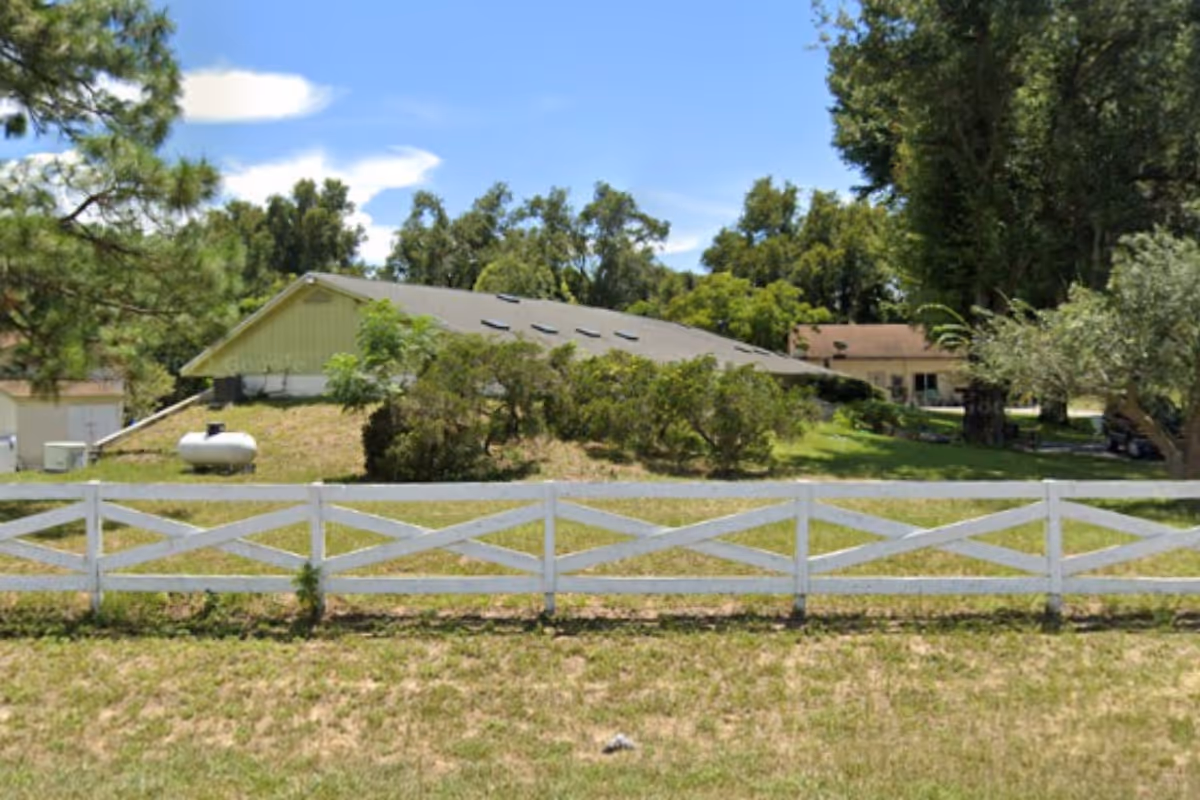 Exterior view of Elders of Mount Dora Assisted Living Facility with white fence and landscaping.
