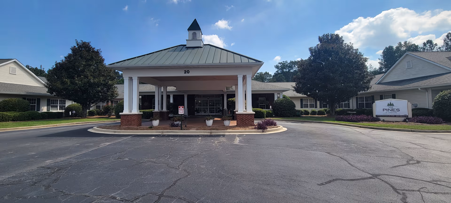 Exterior view of a senior living facility entrance with a porte-cochere and circular driveway