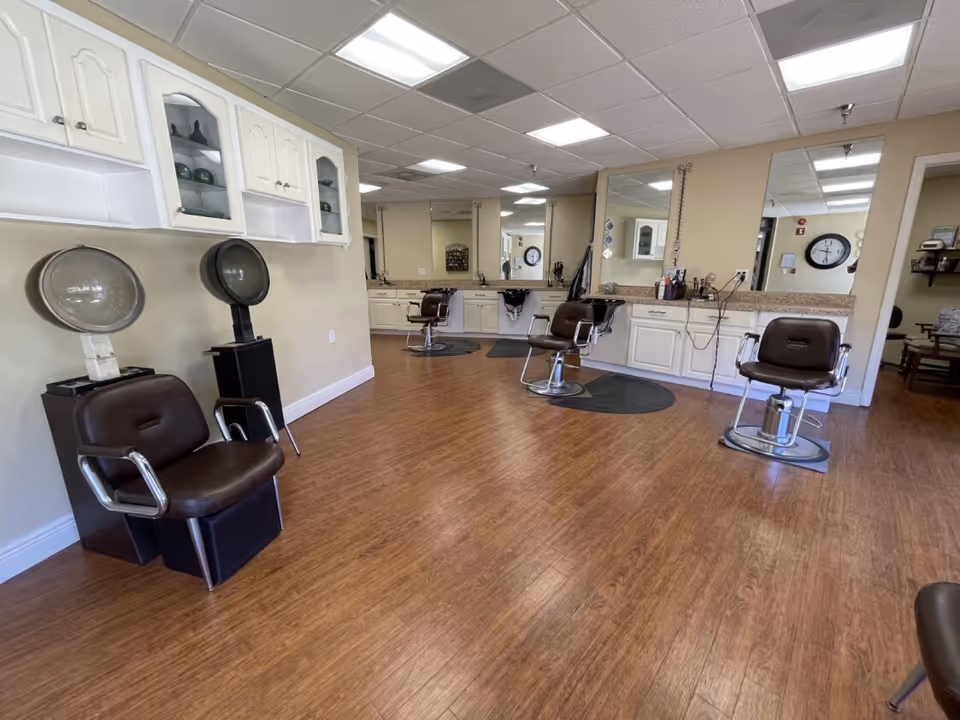 Senior living salon area with white cabinetry, mirrors, and multiple styling chairs.