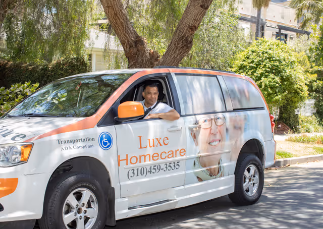 A Luxe Homecare van parked on a sunny street with a driver in the front seat.