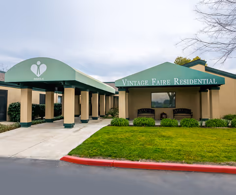 Front exterior of Vintage Faire Residential with walkway, awnings, and green landscaping.