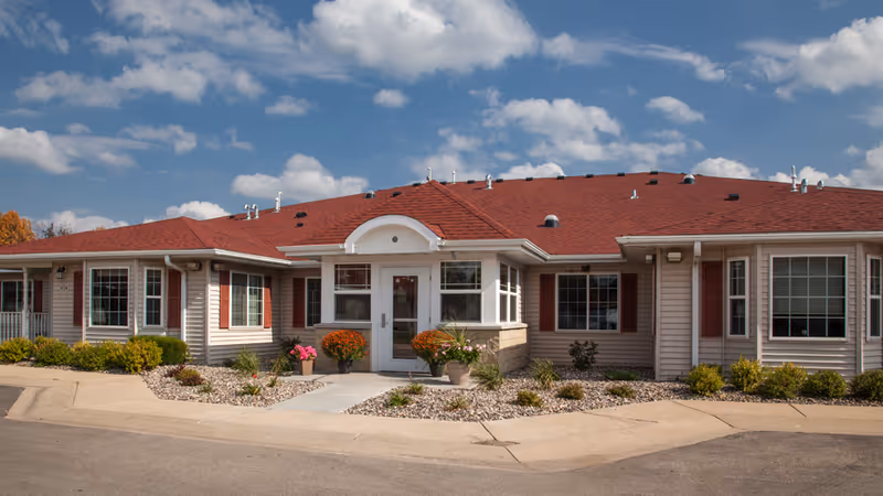 Single-story senior living facility with red roof and landscaped front entrance.