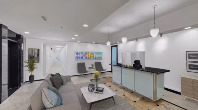 Modern senior living lobby with reception desk, lounge seating, artwork, and hallway.
