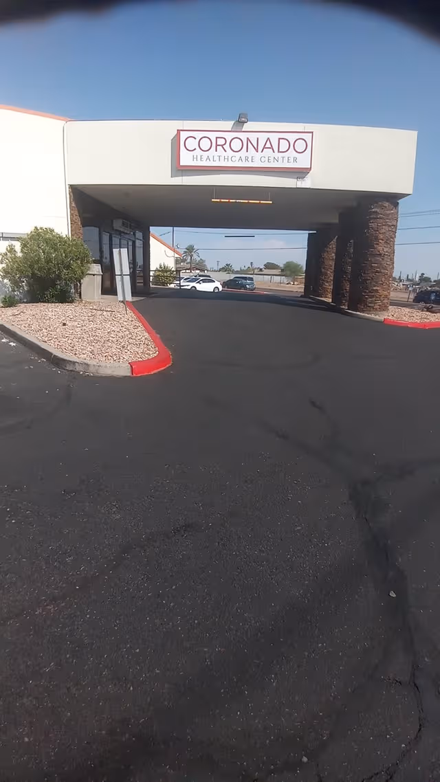 Front entrance of Coronado Healthcare Center with driveway and stone columns.