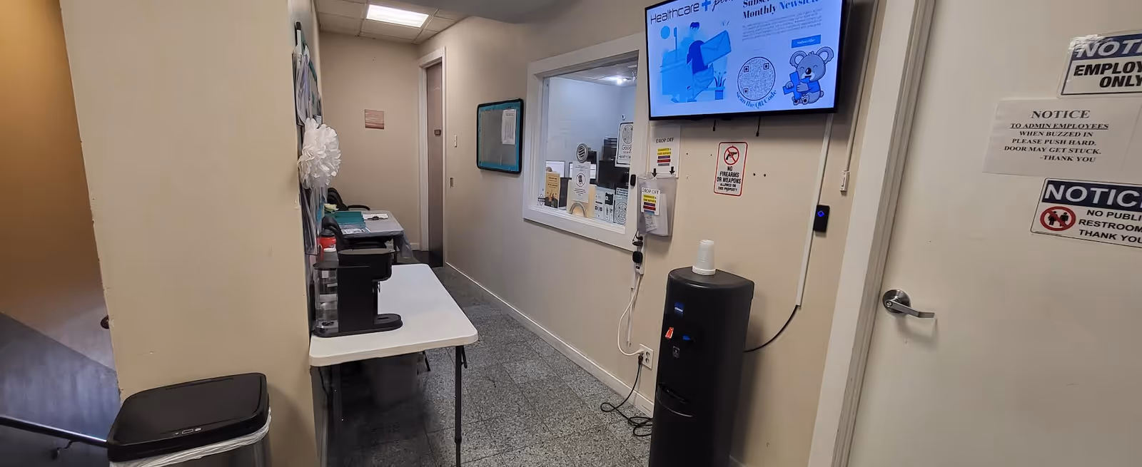 Interior hallway of a senior facility with a desk, water cooler, and notices.