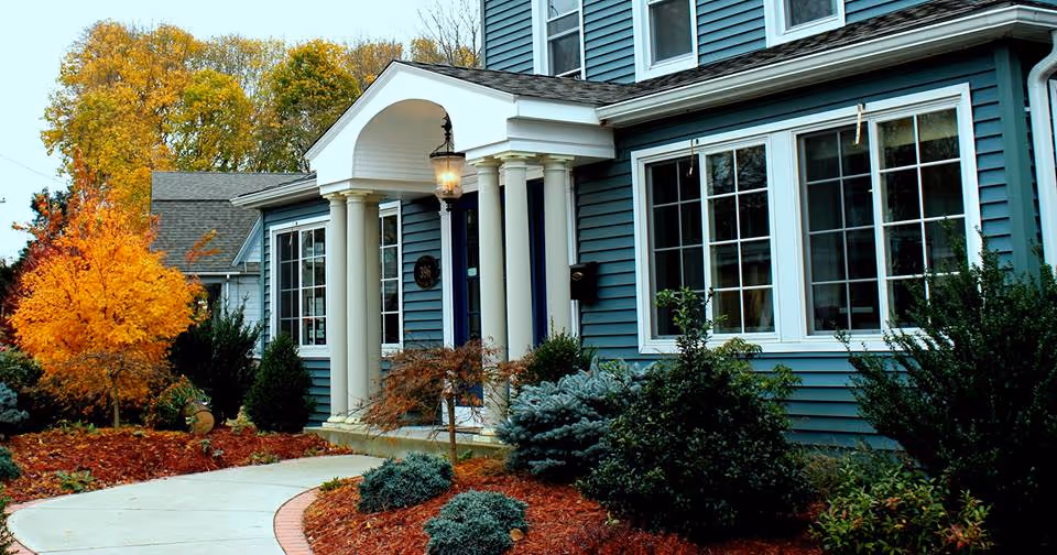 Blue two-story building with white columns, large windows, and landscaped front yard.