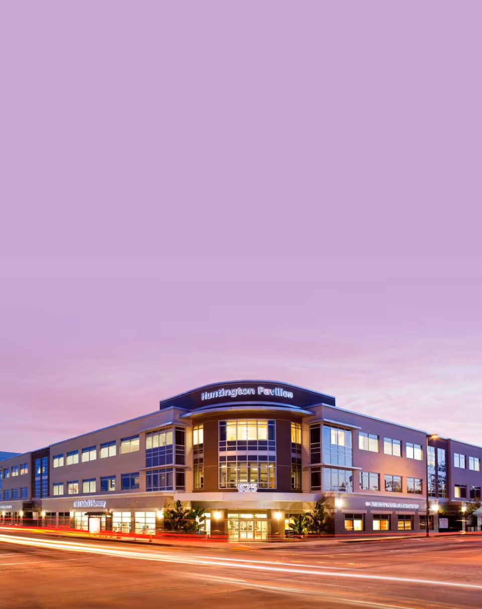 Exterior view of a modern multi-story senior living building at dusk.