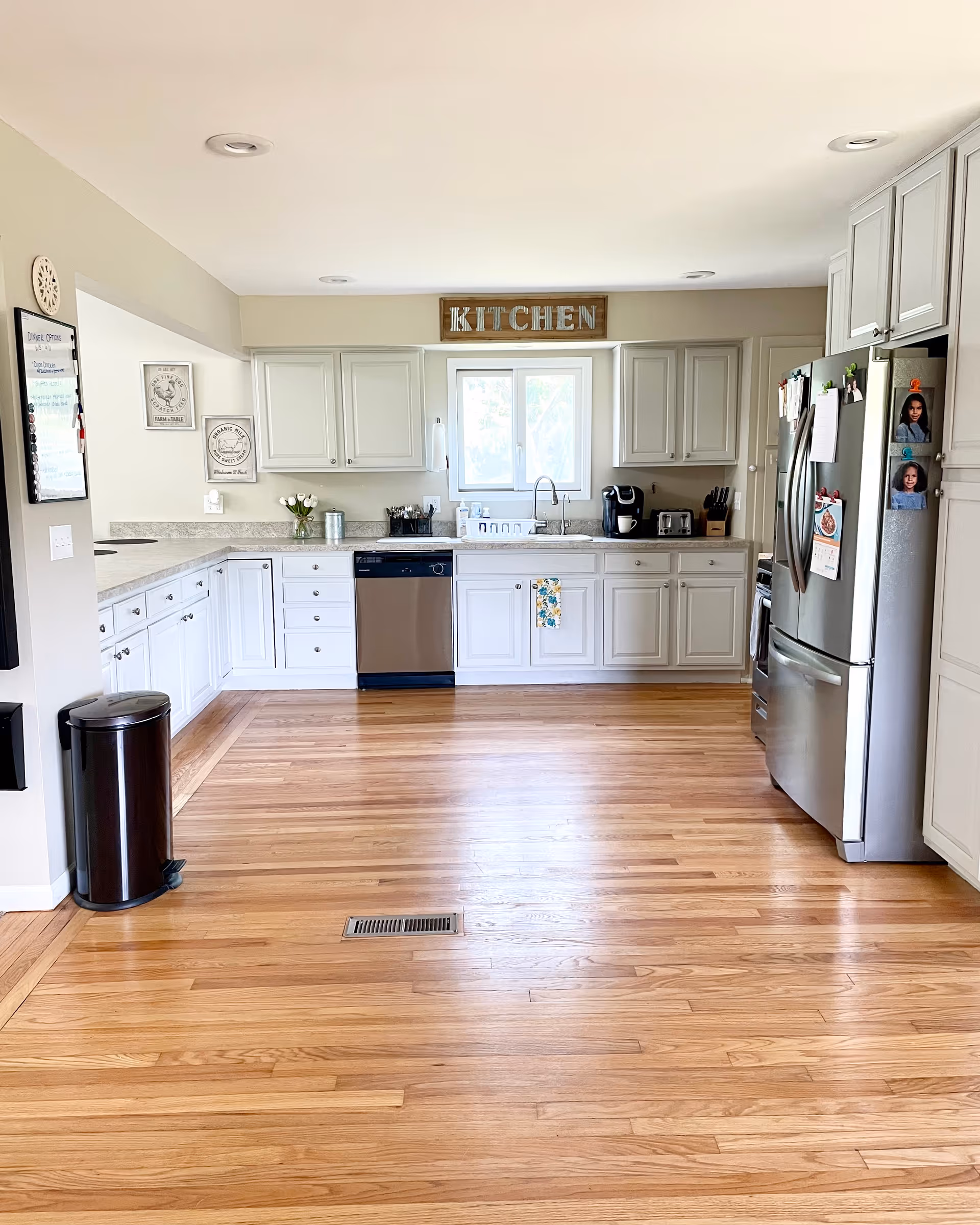 Bright, modern kitchen with white cabinets, stainless appliances, and hardwood floors in a senior living facility.