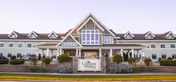 Front exterior of a large multi-story assisted living building with a central entrance and a sign that reads "Comforts of Home".