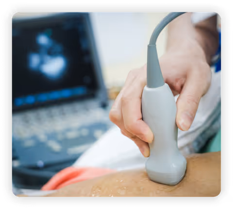 Close-up of ultrasound probe on patient’s skin with screen in background.