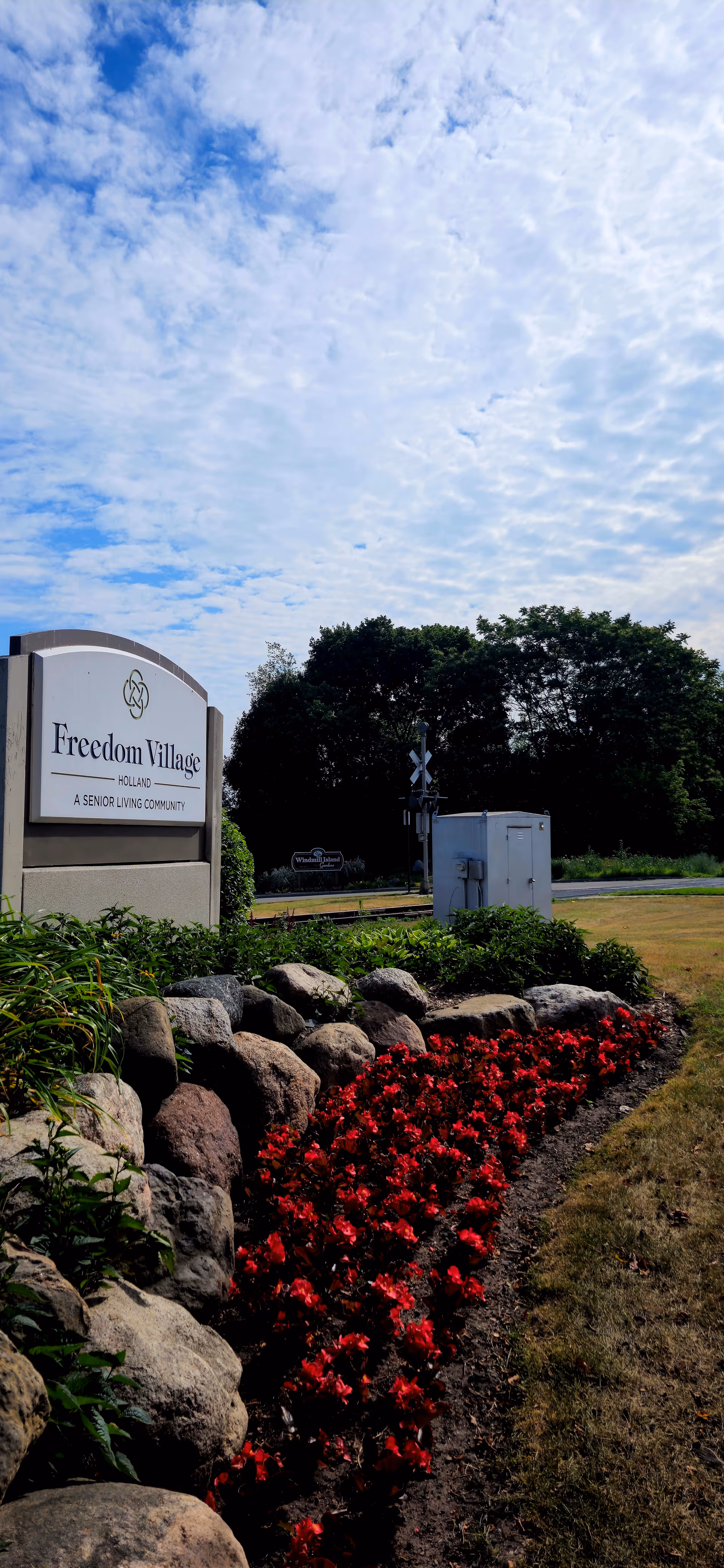 Entrance sign for Freedom Village senior living, with red flowers and rocks.