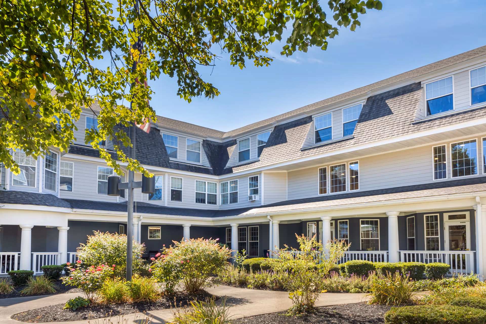 Exterior view of a white senior living facility with a courtyard and columns.
