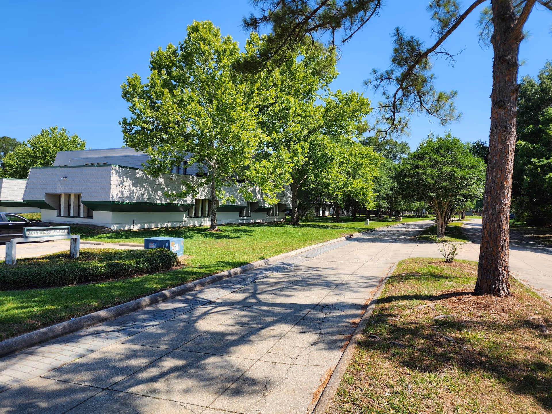 Exterior view of Caravelle Care facility with a tree-lined walkway and modern white building.