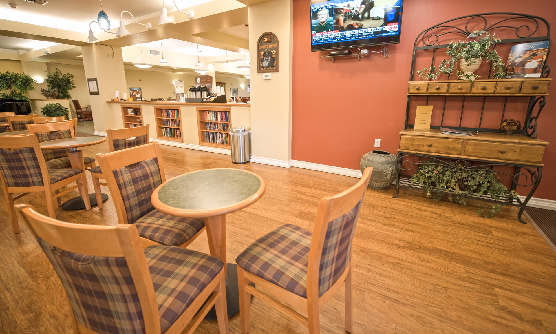 Common lounge area with round tables, plaid chairs, and a red-walled cabinet.