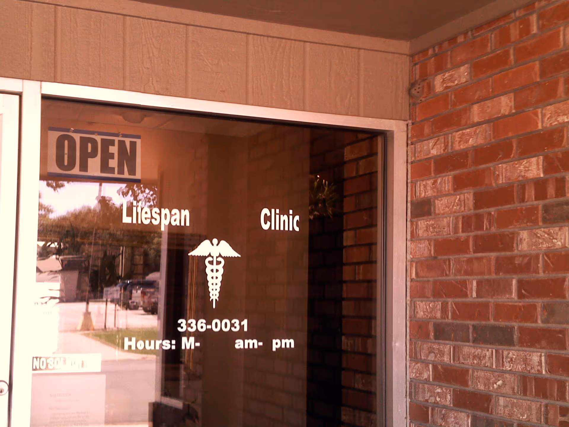 Glass entrance door displays OPEN and Lifespan Clinic branding against a brick exterior.