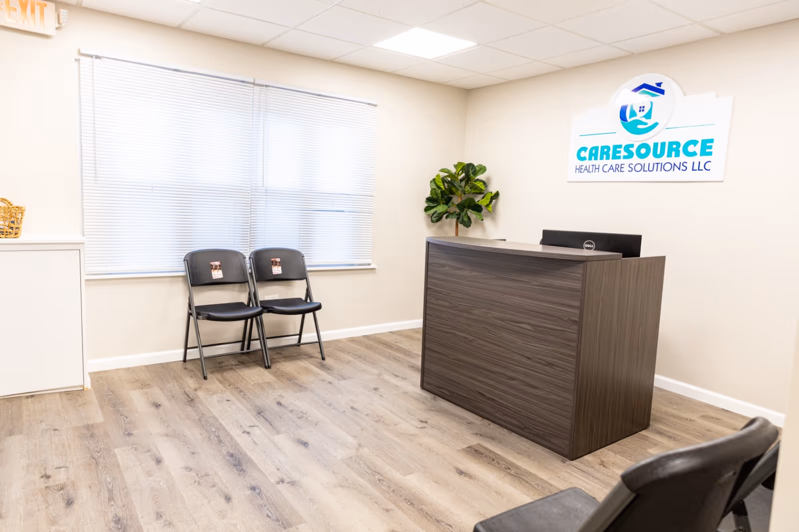 A modern reception area of a CareSource facility with a desk, two chairs, and a plant.