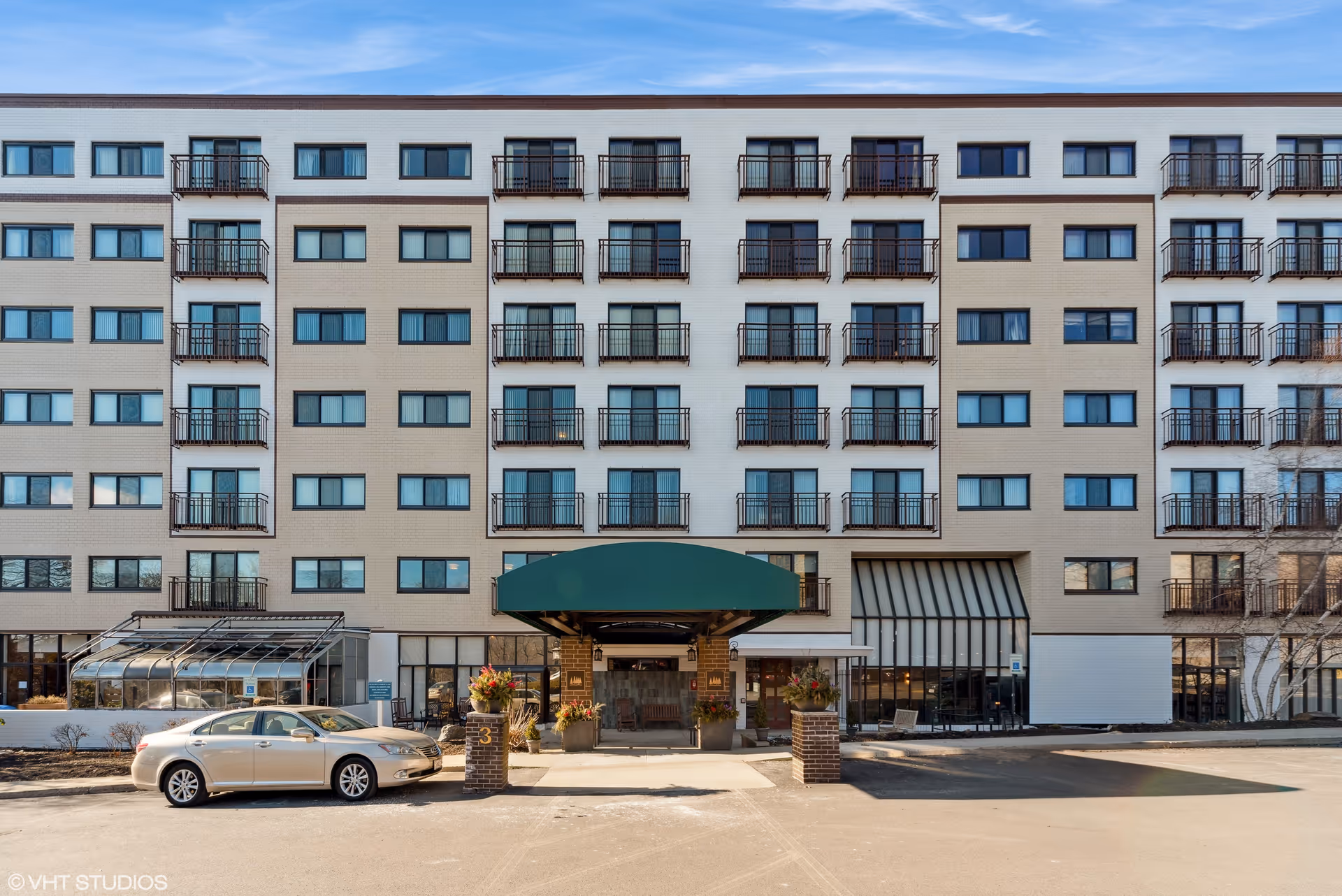 Exterior view of AVIVA Country Club Heights with a glass entry and green awning.