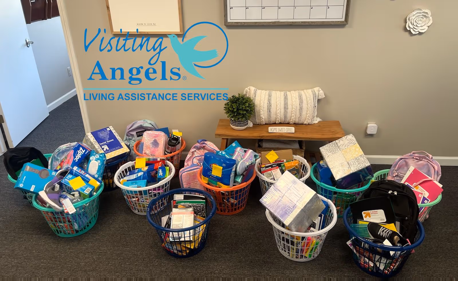 Indoor facility area with Visiting Angels sign and baskets of supplies.