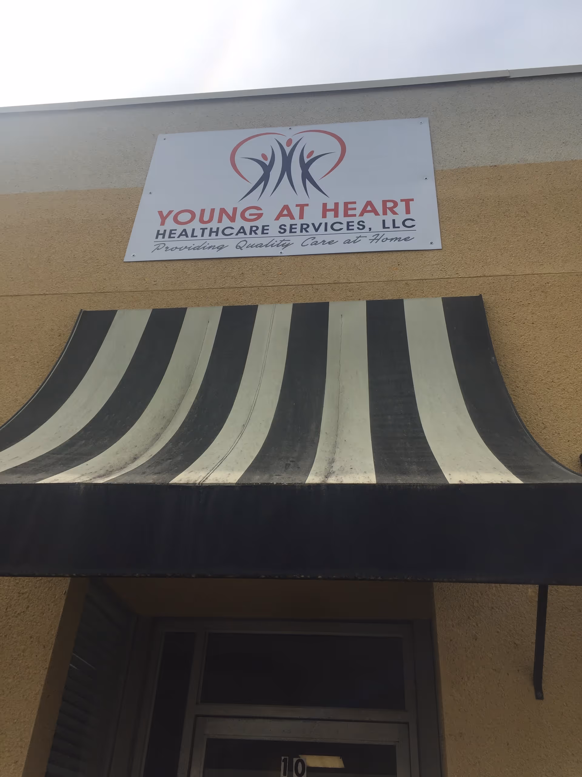 Front exterior of Young at Heart Healthcare Services with striped awning and sign