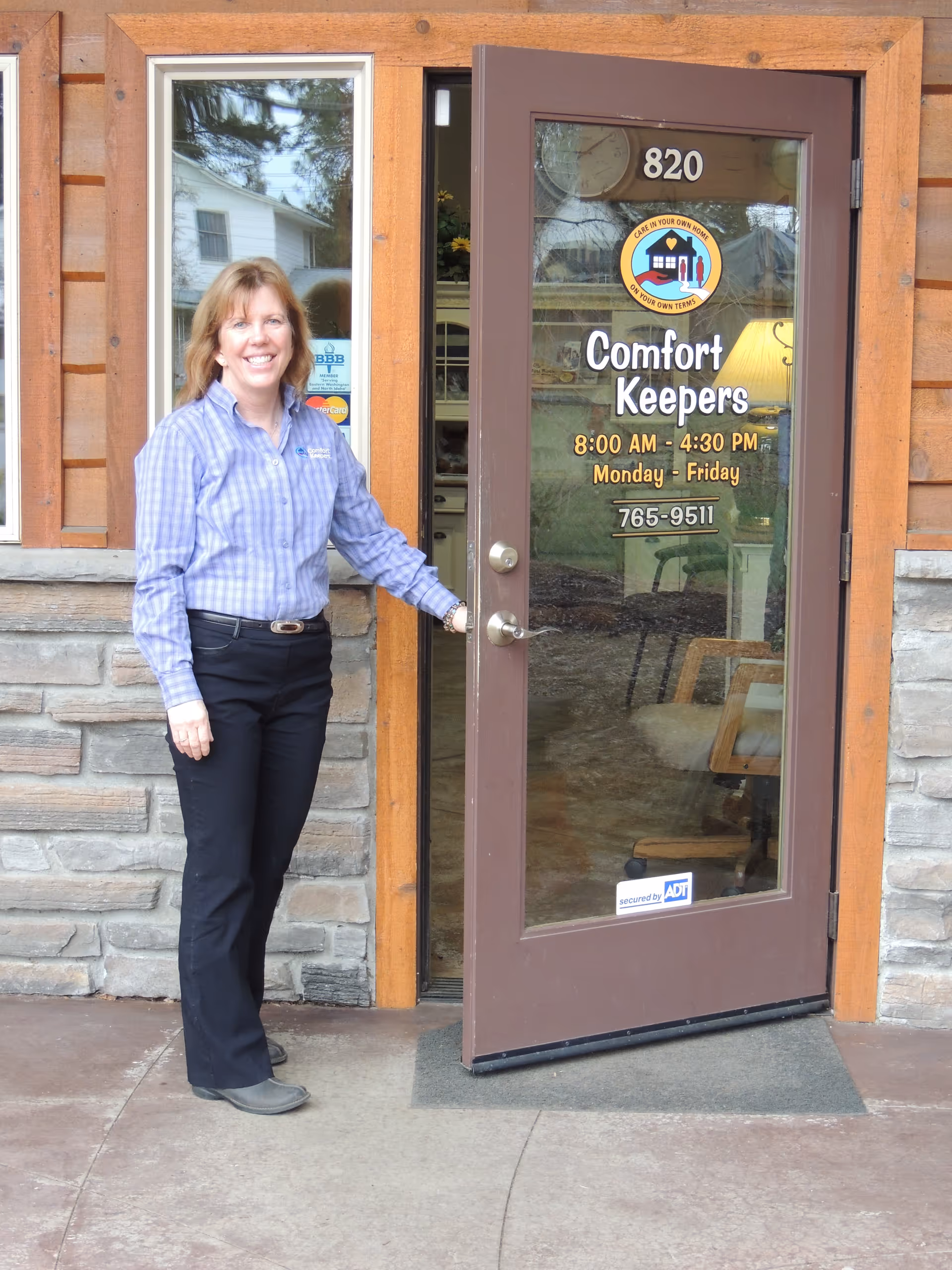 A staff member stands at the Comfort Keepers front door of a facility.