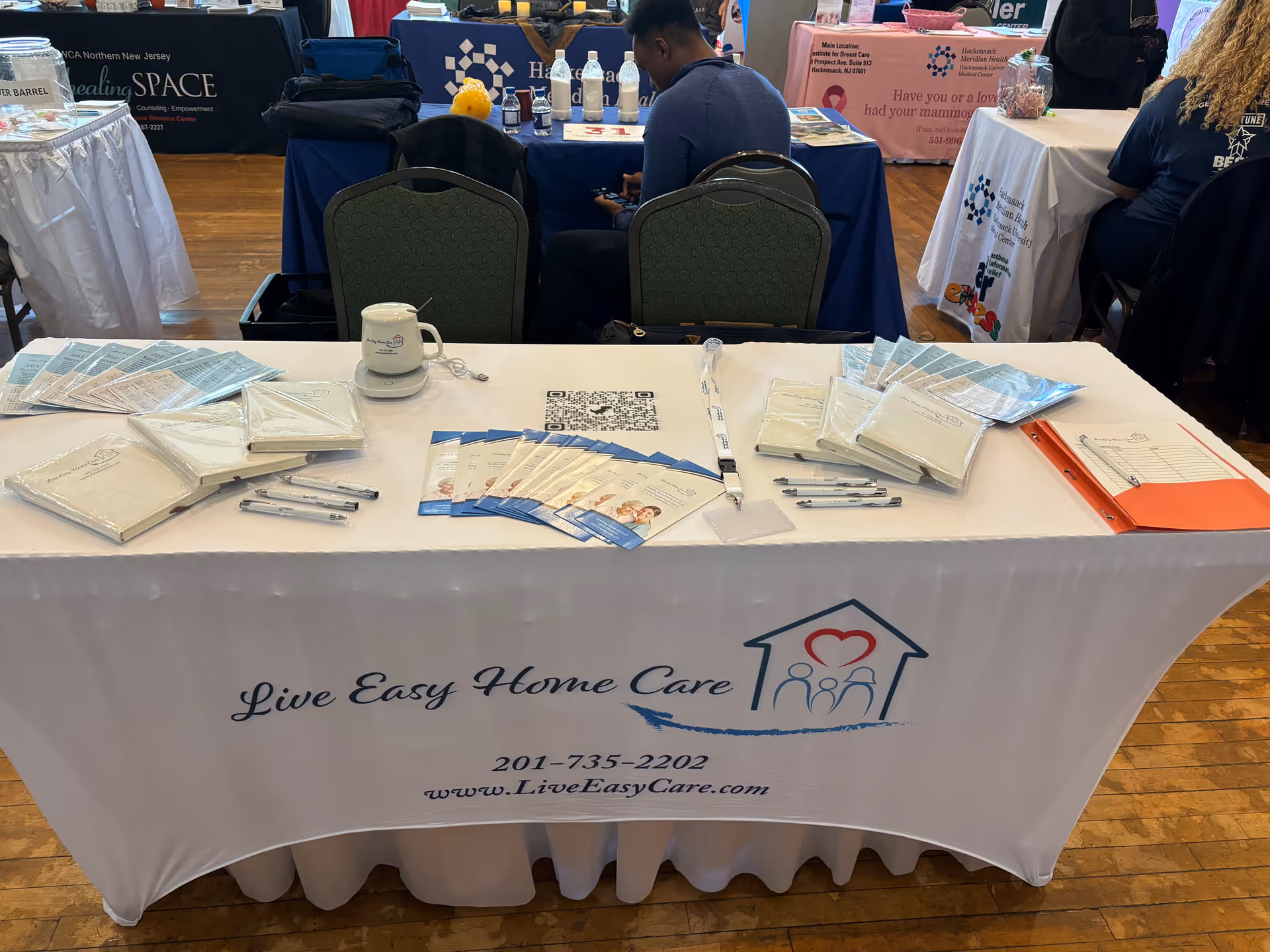 Table covered with Live Easy Home Care brochures and pens at an indoor expo booth