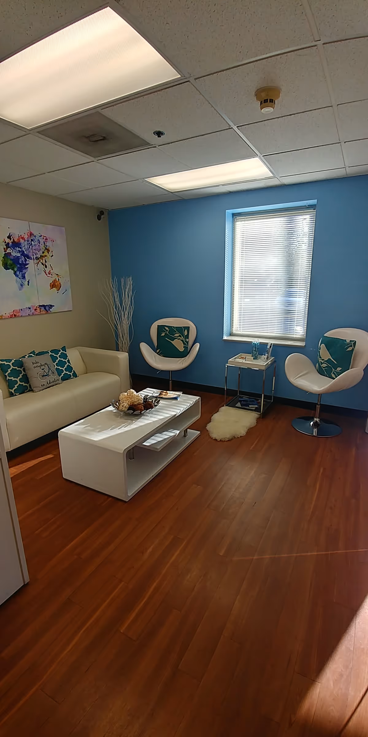 Modern lounge area with white sofa, two chairs, coffee table, and blue accent wall.