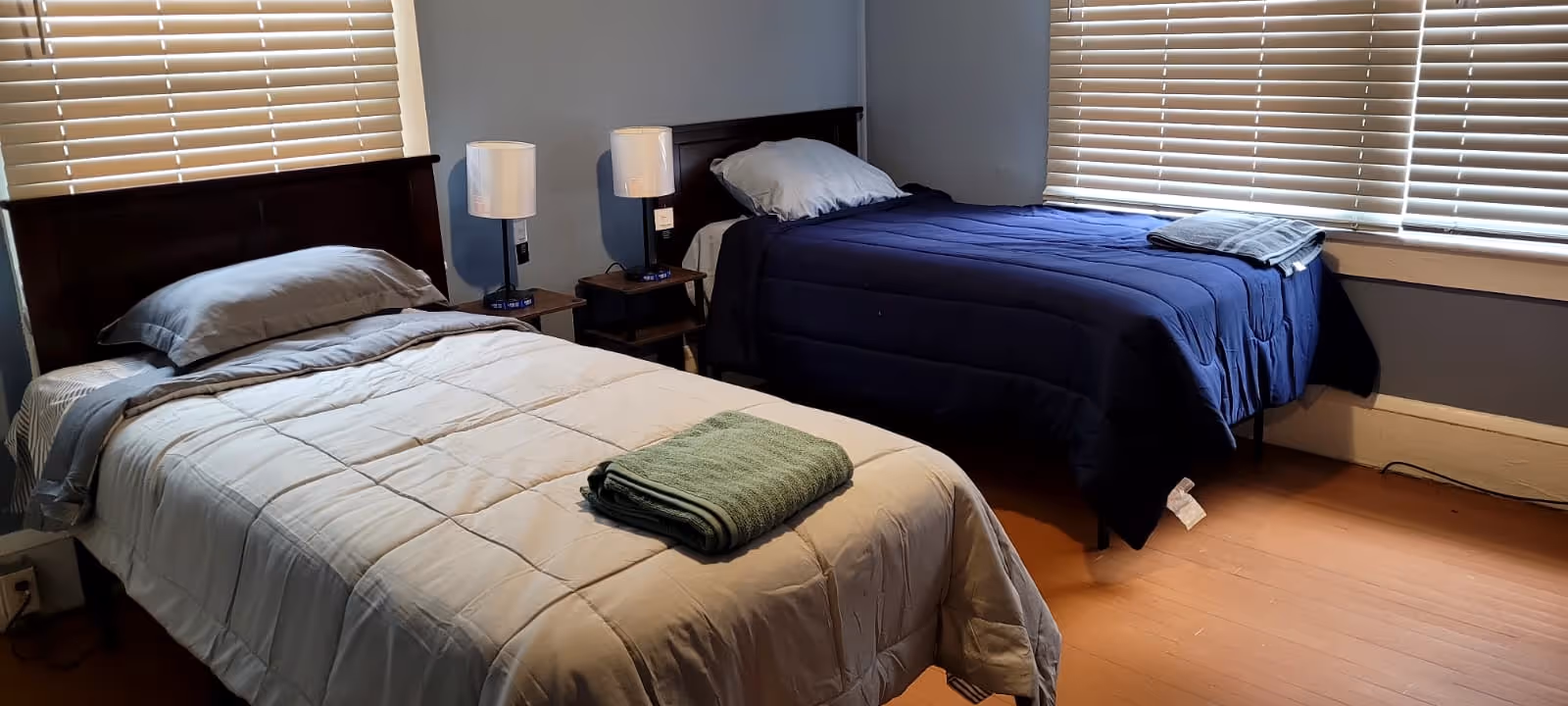 Two twin beds with nightstands and lamps in a shared bedroom.