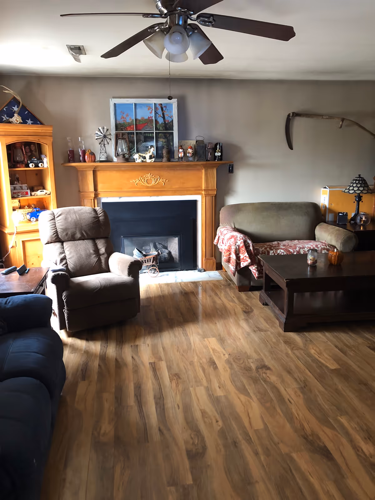 Cozy living room featuring a wood fireplace, ceiling fan, and assorted decor.