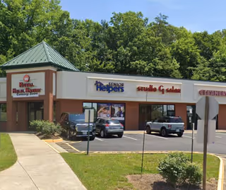 Strip mall storefronts with Senior Helpers signage and parked cars in front.