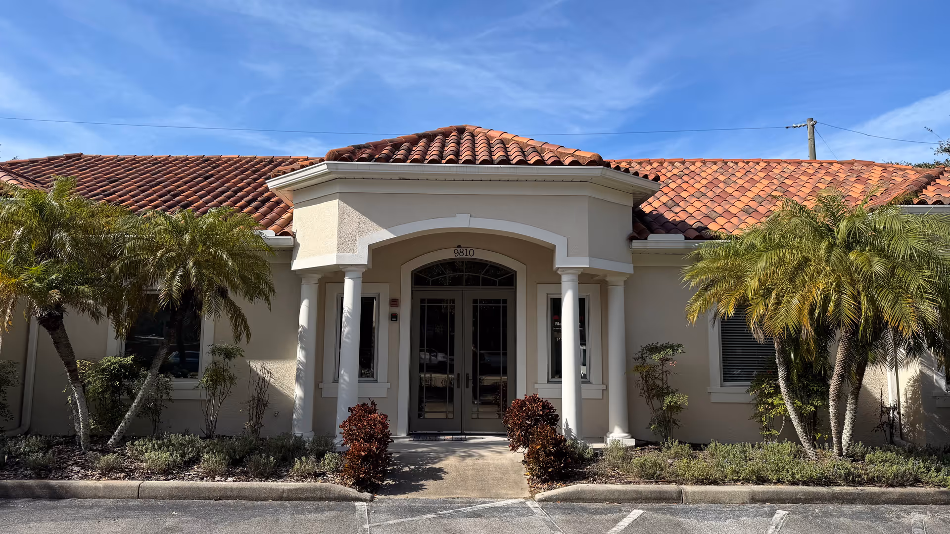 Exterior view of Visiting Angels Senior Home Care Tampa building entrance with columns and palm trees.