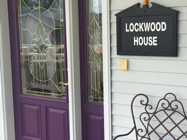 Purple front doors with stained glass and a Lockwood House sign on siding.
