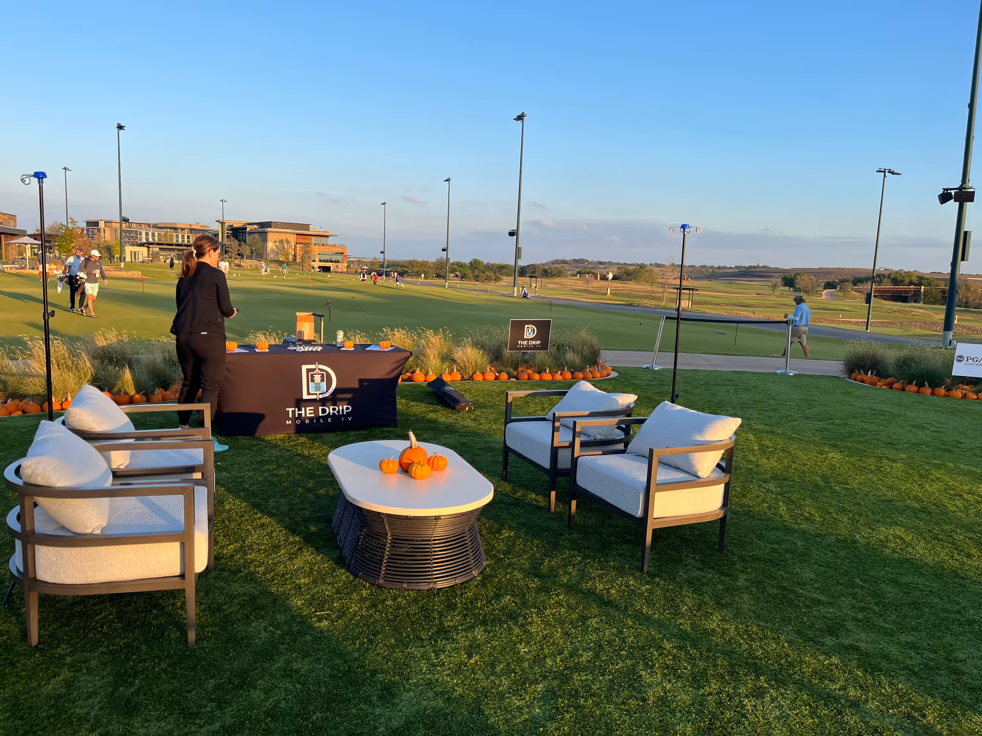 Outdoor lounge setup with The Drip Mobile IV branded table and pumpkin decor.
