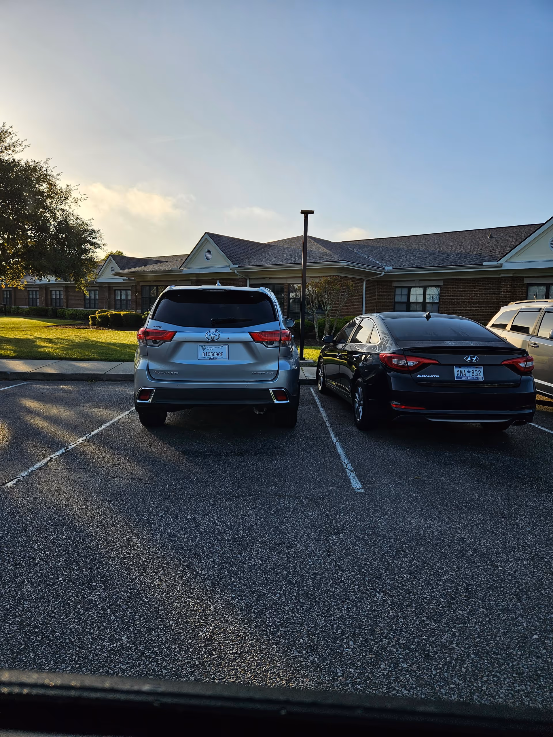 Parking lot in front of a single-story brick senior facility with two cars parked.