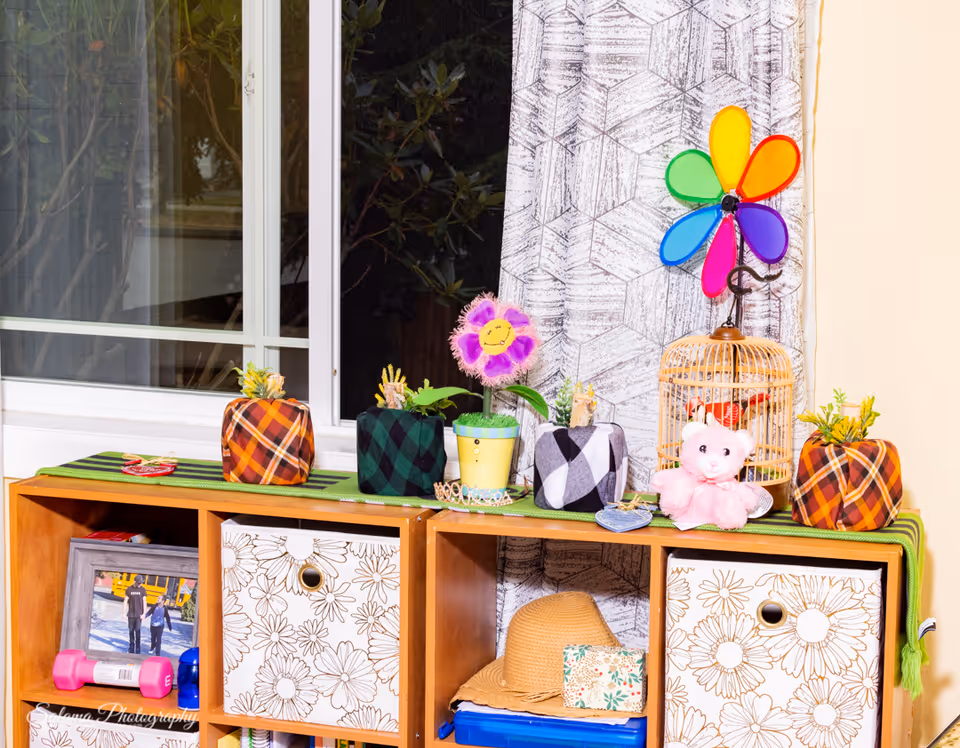 Colorful decorative items arranged on a wooden cabinet by a window.